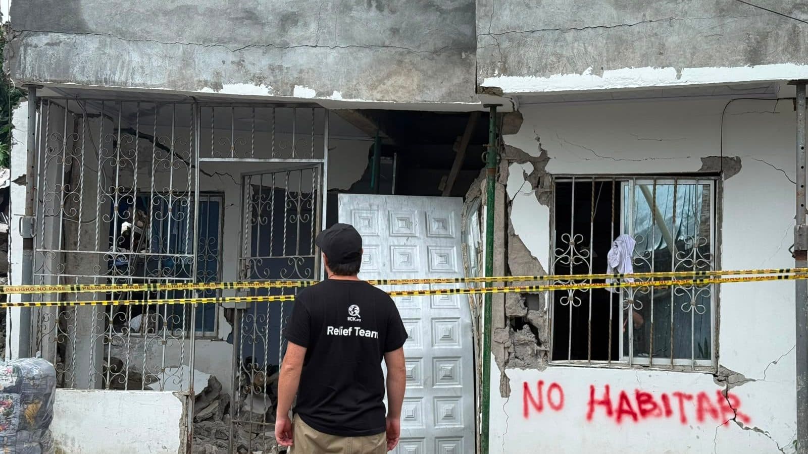 A relief worker stands before a cracked house marked unfit to live in, in Quibdó, Chocó