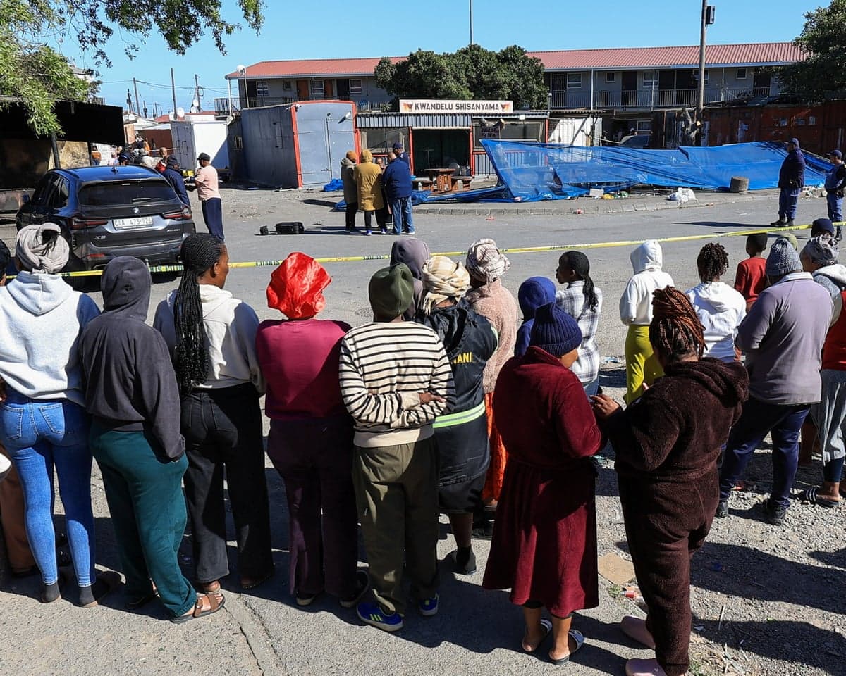 People gather at the store in Lwandle, near Cape Town, where 10 people were killed.