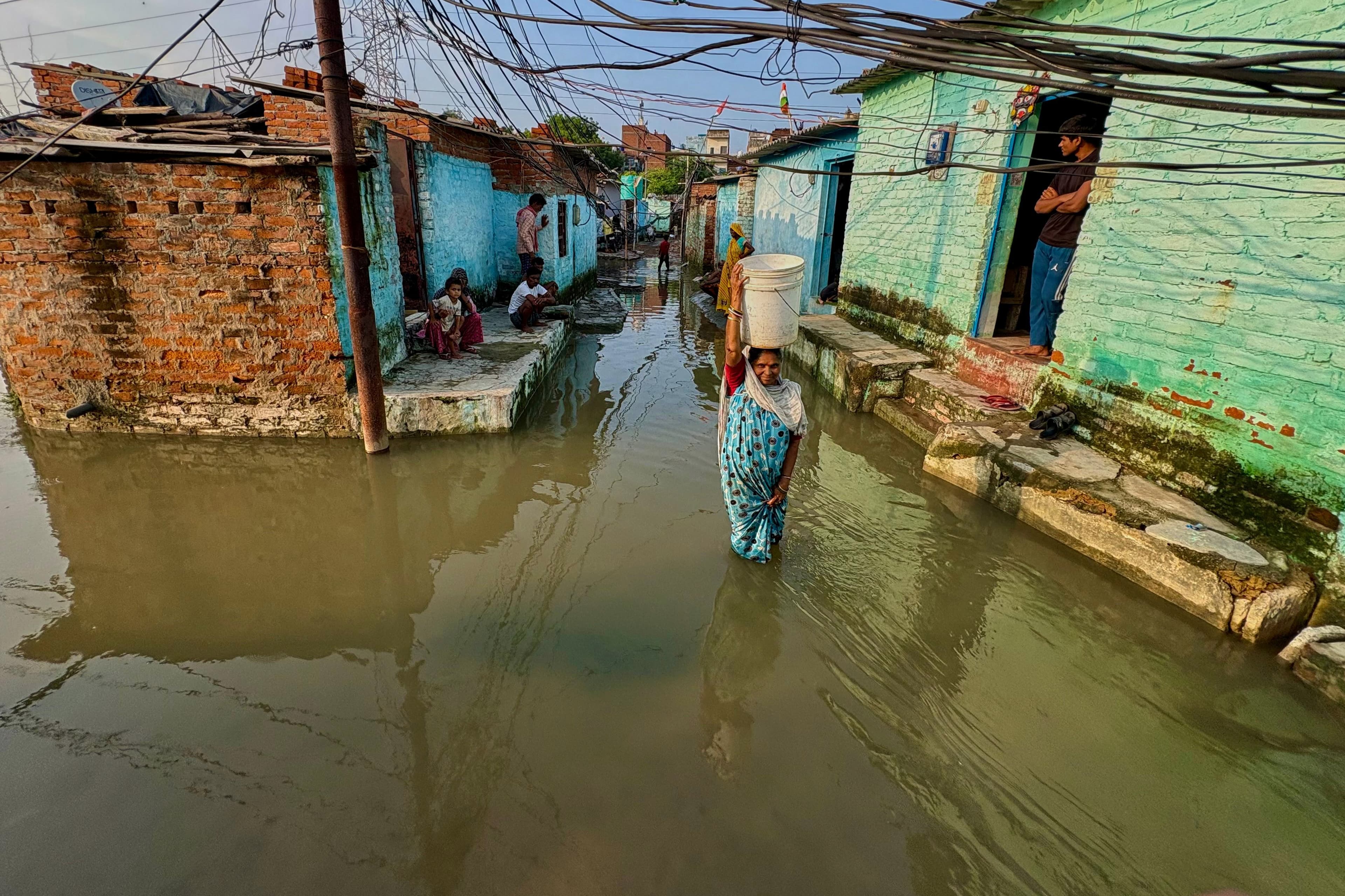 A woman wades through floodwaters in her neighborhood following heavy rains in Kanpur, India, on Sept. 22, 2026.