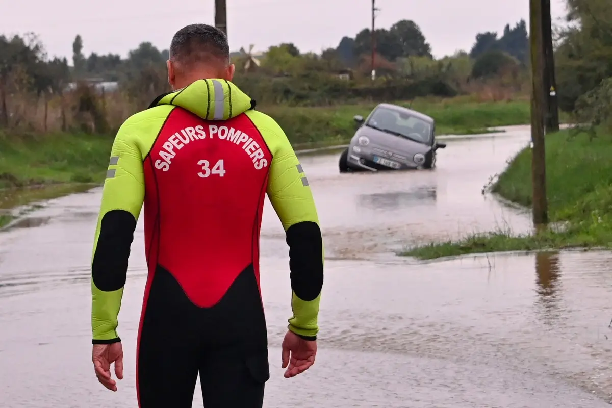 A firefighter looks at a car stranded in a flooded street in Lunel, near Montpellier, southern France, on 20 October 2026.