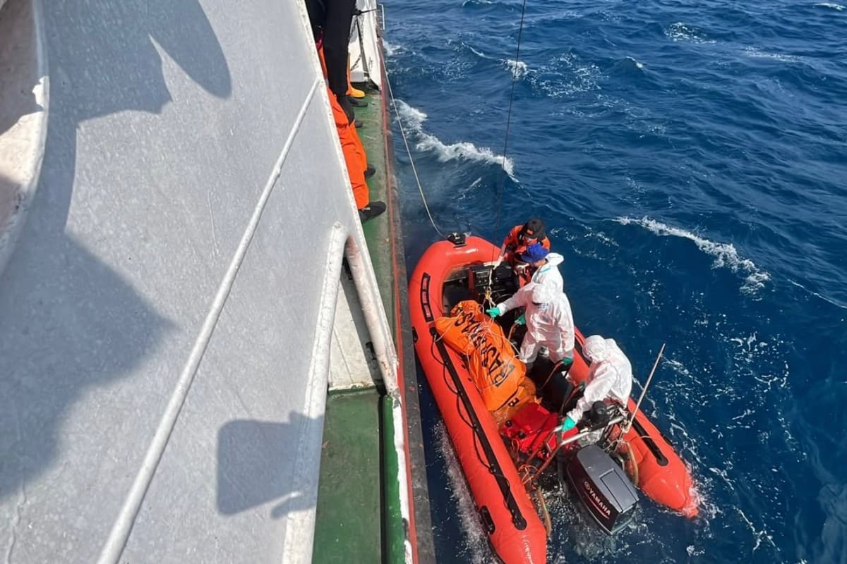 Search and rescue personnel onboard a small rigid inflatable boat with a victim from the MV Virgo Transport 8, alongside their ship in the Java Sea off South Kalimantan.